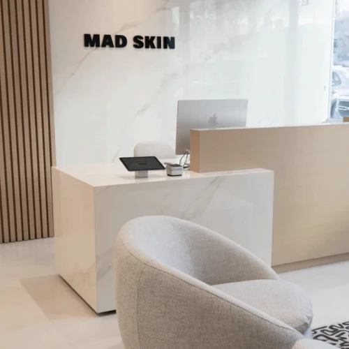 A modern reception desk situated in a well-lit room with neutral-colored walls and minimal decor. A modern reception desk situated in a well-lit room with neutral-colored walls and minimal decor.